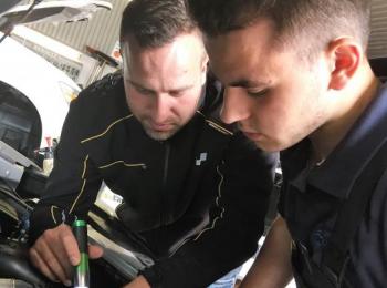 Zwei Mitarbeiter leuchten in den Motorraum eines Fahrzeuges