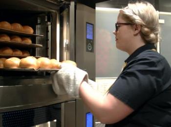 Azubi holt Brötchen aus dem Ofen