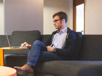 Junger Mann auf Sofa mit Notebook