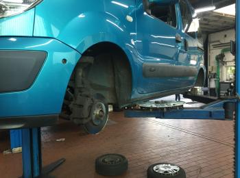 Der Reifen eines metallicblauen Fahrzeugs wird gewechselt.