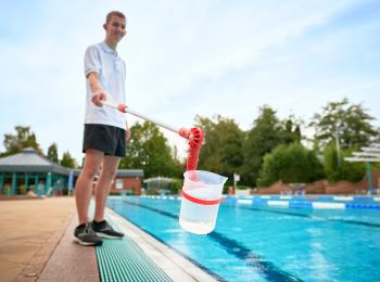 Azubi entnimmt eine Wasserprobe aus dem Schwimmbecken