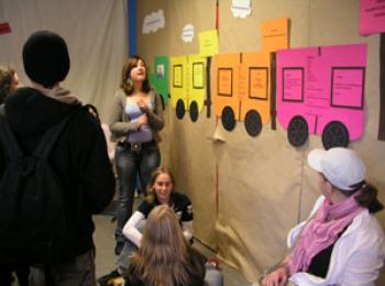 Schüler/innen vor eine Wand mit Projektbeschreibungen