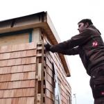 Mitarbeiter befestigt Holzschindeln
